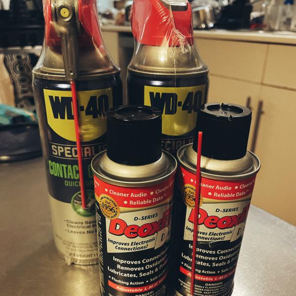 Four brand new spray cans of contact cleaner on a kitchen table