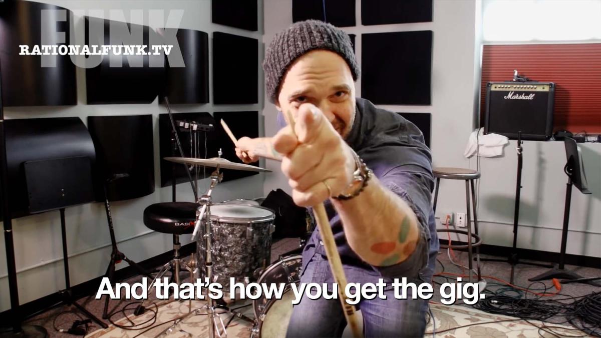 Screen capture of a Rational Funk episode with Dave King pointing at the camera holding a drumstick. The caption, “And that’s how you get the gig.” appears at the bottom of the image.
